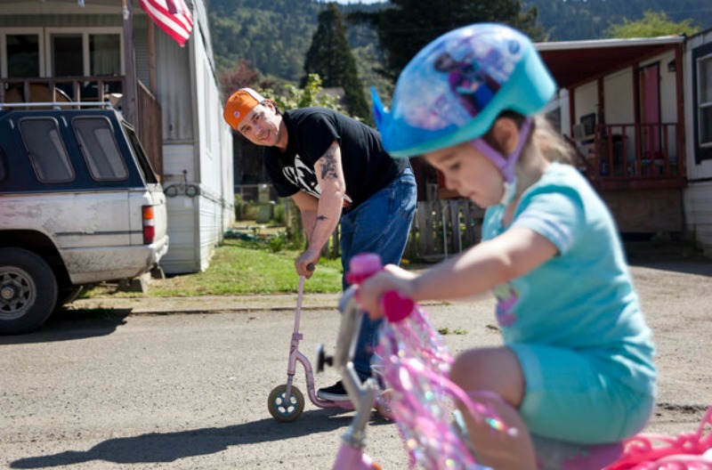 ·üýÀQ uc÷__·ìeüïª[Kåù=Ëù·ÿÙBryan Thouvenel rides on a scooter while watching his daughter Harmony, 5, on her bike in front of their house in Myrtle Creek, Saturday April 3, 2016. Thouvenel and Harmony were recently reunited a