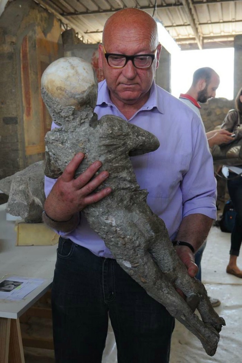 Stefano Vanacore, director of the laboratory of Pompeii Archaeological Site, carries a petrified victim of the eruption of Vesuvius volcano in 79 BC, during the restoration work and the study of 86 casts, on May 20, 2015 in Pompeii Archaeological site. AFP PHOTO / MARIO LAPORTA (Photo credit should read MARIO LAPORTA/AFP/Getty Images)