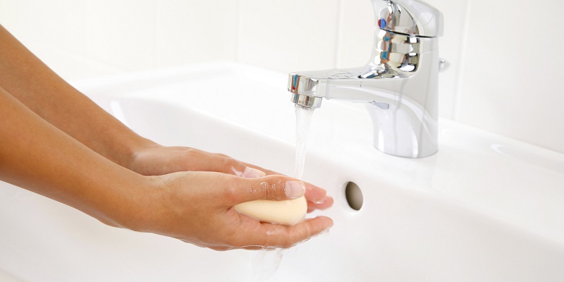 Woman washing hands with bar of soap in sink, close-up