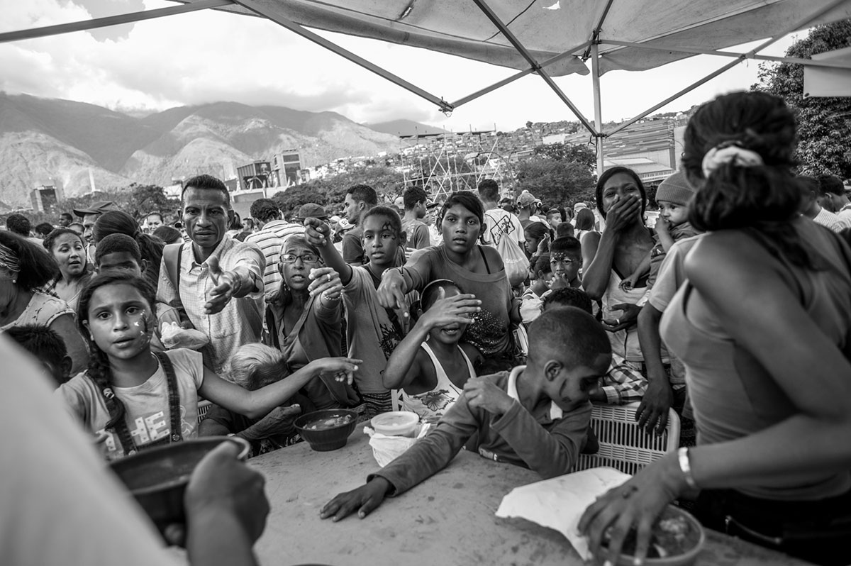 Personas esperando un plato de sopa gratis en la Iglesia Evangélica de Petare.