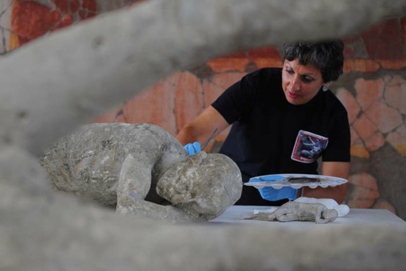 A restorer cleans and analyses a petrified victim of the eruption of Vesuvius volcano in 79 BC, as part of the restoration work and the study of 86 casts in the laboratory of Pompeii Archaeological Site, on May 20, 2015 in Pompeii. AFP PHOTO / MARIO LAPORTA (Photo credit should read MARIO LAPORTA/AFP/Getty Images)