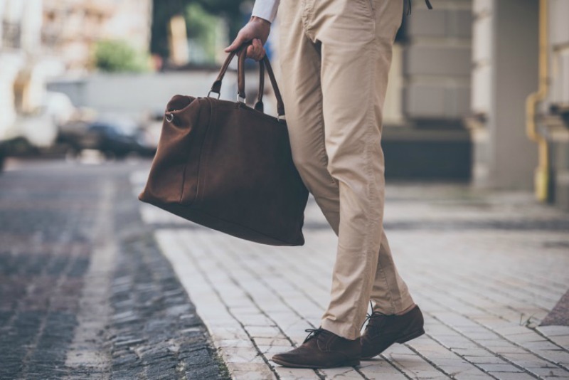Close-up of man holding leather bag while walking outdoors